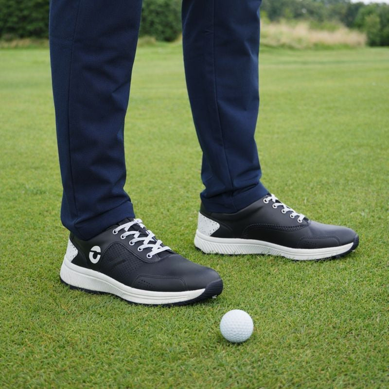 Forza Men’s Waterproof Golf Shoes with white soles on a grassy field, close-up of feet and golf ball.